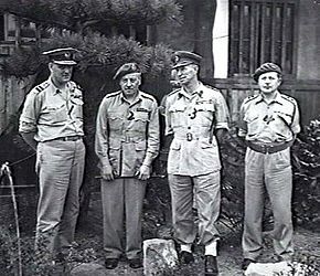 Full-length outdoor portrait of four men in light-coloured military uniforms