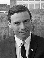 A black and white photograph of a man in a suit and tie looking at the camera