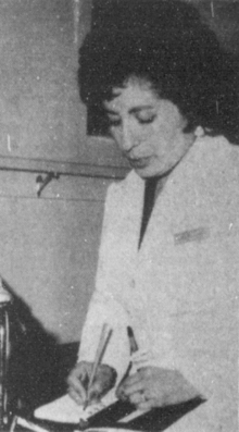 A nurse in a uniform writing notes in a book