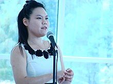 Young Asian woman speaking at a microphone