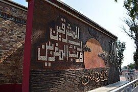 Monument on the mosque's west side featuring Quranic verse 55:17.