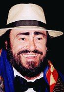 Pavarotti in a black bowtie, a white brimmed hat, a colourful scarf and a big smile.