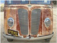 Front end with grill, emblem, and teardrop headlights