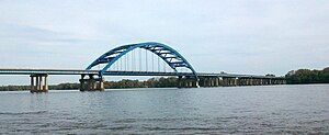 A bridge with a large arch crosses a river.