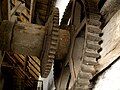 Inside threshing barn: gear wheels on end of drive shaft, where further gears and drive belts would be attached for driving various machines