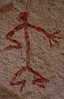 Humanoid stick figure painted on a rock wall in red. The figure is shown in Stylistic group C.