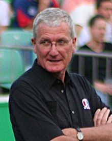 A head and shoulder shoot of an Englishman standing at the Taunton Cricket Ground, wearing a black shirt and spectacles