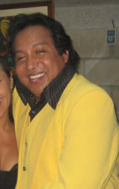 A man with a yellow sweater smiling.