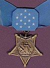 A light blue neck ribbon with a gold star shaped medallion hanging from it. The ribbon is similar in shape to a bowtie with 13 white stars in the center of the ribbon.