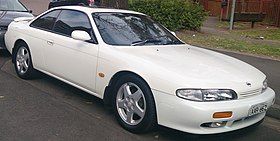 Front-three-quarter view of a two-door car with door mirrors, a sunroof, and a rear spoiler