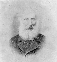 Black and white head and shoulders portrait of Peter Imlay, a man with a large white beard