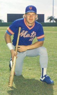 A man in a blue baseball jersey and cap with gray pants