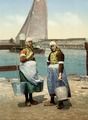 Two girls on the isle of Marken, the Netherlands, carrying water buckets on a yoke (circa 1900)