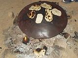 Flatbread baking over a fire on a convex saj