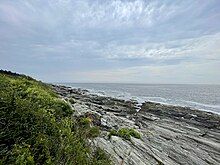 The rocky shoreline of Two Lights State Park with the open ocean beyond it.