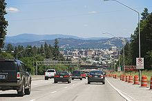 A freeway with traffic cones carrying traffic downhill into a large city