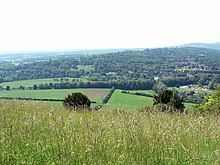 view of hills, trees and fields across a meadow