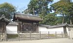 A small wooden roofed gate with chrysanthemum motifs and Chinese style gables on the side.