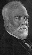 Bust portrait photograph of an old man, mostly balding with some whispy white hair on top, with a trimmed white goatee.