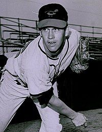 A man in a light baseball uniform and dark cap