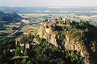 Photo of a castle ruin atop a steep bluff with generally flat countryside stretching to the horizon.