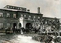 A sepia photograph of the Government House during the Royal Visit. A horse-drawn carriage is in front of the building.