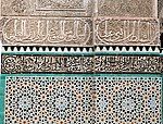 Zellij tilework featuring geometric motifs (below), with sgraffito-type tiles (middle) and stucco decoration (above) featuring Arabic calligraphy