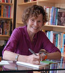 Blume smiling while signing a book