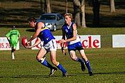 Sydney AFL league East Coast Eagles AFC player uses a handball pass to dispose of the ball before he is tackled by a Campbelltown Kangaroos AFC opponent.