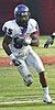 An American football player runs down the field, dressed mostly in white.