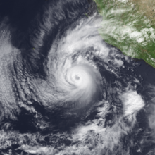 A photograph of a powerful hurricane off the Pacific coast of Mexico; it has a well-defined eye encircled by deep convection, with spiral bands arcing to the north