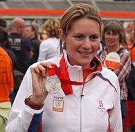 A Dutch woman holding an silver Olympic medal in her right hand among a crowd