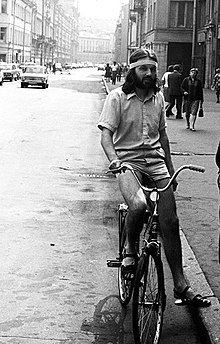 A long-haired man riding a bicycle on a city street