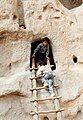 Children climb a ladder to explore the cave rooms at Bandelier National Monument, New Mexico