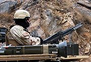 A 19th Group soldier on a Ground Mobility Vehicle variant Humvee provides security with a turret mounted M60 machine gun during a convoy stop in Asadabad, Afghanistan in 2004. An AT4 can be seen in the foreground.