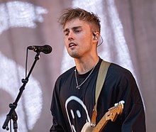 Sam Fender onstage, in a black T-shirt