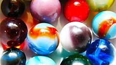 Close-up of a dozen or so marbles in different colors and patterns.