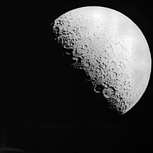 A black-and-white image of Earth's Moon. The terminator is visible as the lower left of its surface is in shadow.