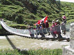 Children are waving the Peruvian flag on the new footbridge across Qañawimayu in Qullpatumayku, Chumbivilcas Province