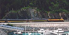 A train and the highway passing a harbor