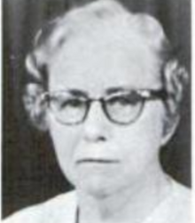 An older white woman with curled grey hair, wearing glasses