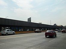 A metro station located in the middle of Río Consolado Avenue, surrounded by several automobiles.