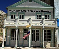 Two-story wooden, white building with blue trim and a large porch