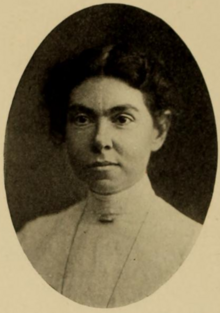 A white woman with dark hair, wearing a high-collared white lace blouse, in an oval frame