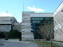 A two-story office building on a college campus with W U S F - T V signage