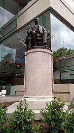 Bronze statue of a seated man on a round pillar