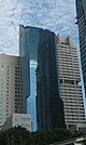 Distant ground-level view of a 40-story building with a blue glass facade; the building has a rectangular cross-section and a diagonal roofline.