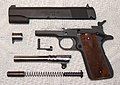 A M1911A1 pistol disassembled and showing the locking grooves on the barrel.