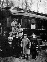 black and white photograph of five men in military uniforms standing side-to-m right, seen outside his railway carriage No. 2419 D in the Forest of Compiègne.