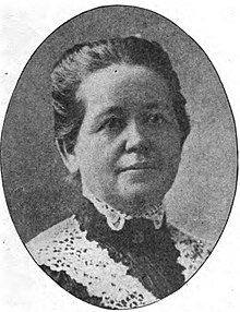 A middle-aged white woman, hair drawn back and up, wearing a high-collared lace-trimmed dress.